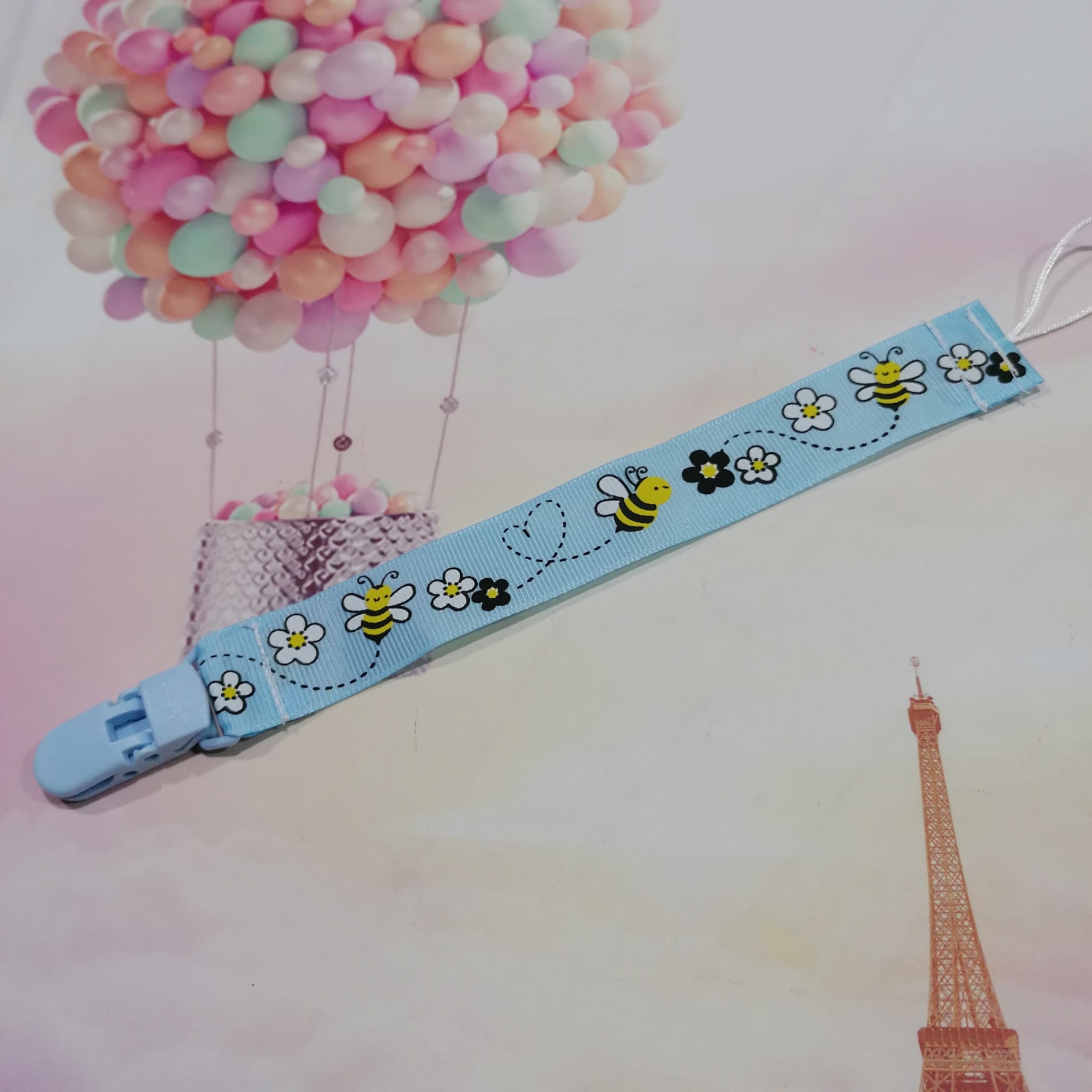 Prendedor azul claro para chupeta com padrão de abelhas e flores
