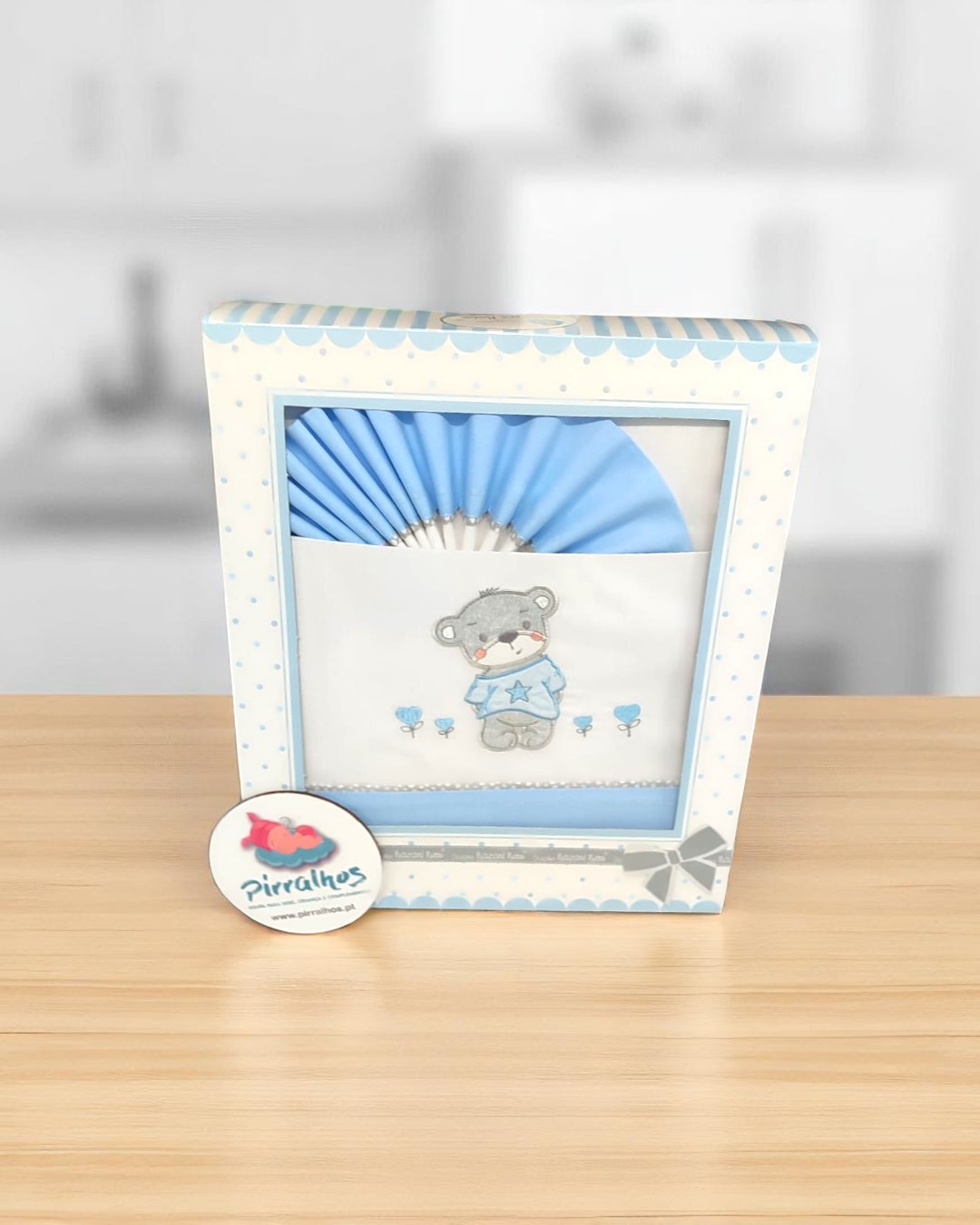 Fralda branca com desenho de urso e flores azuis em embalagem azul claro com bolinhas.