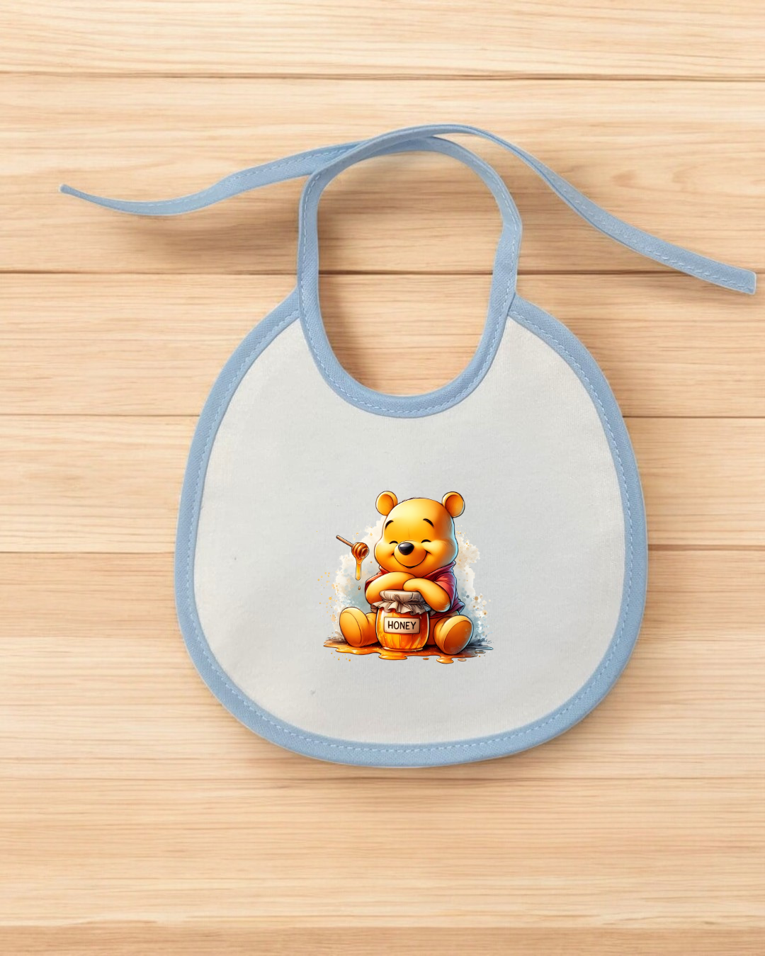 Babete branco com borda azul e estampa de ursinho com pote de mel