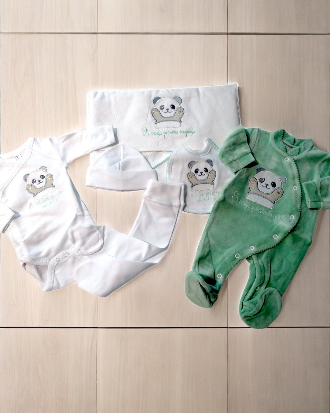 Conjunto de roupa para bebé com desenho de panda e texto comemorativo em branco e verde.