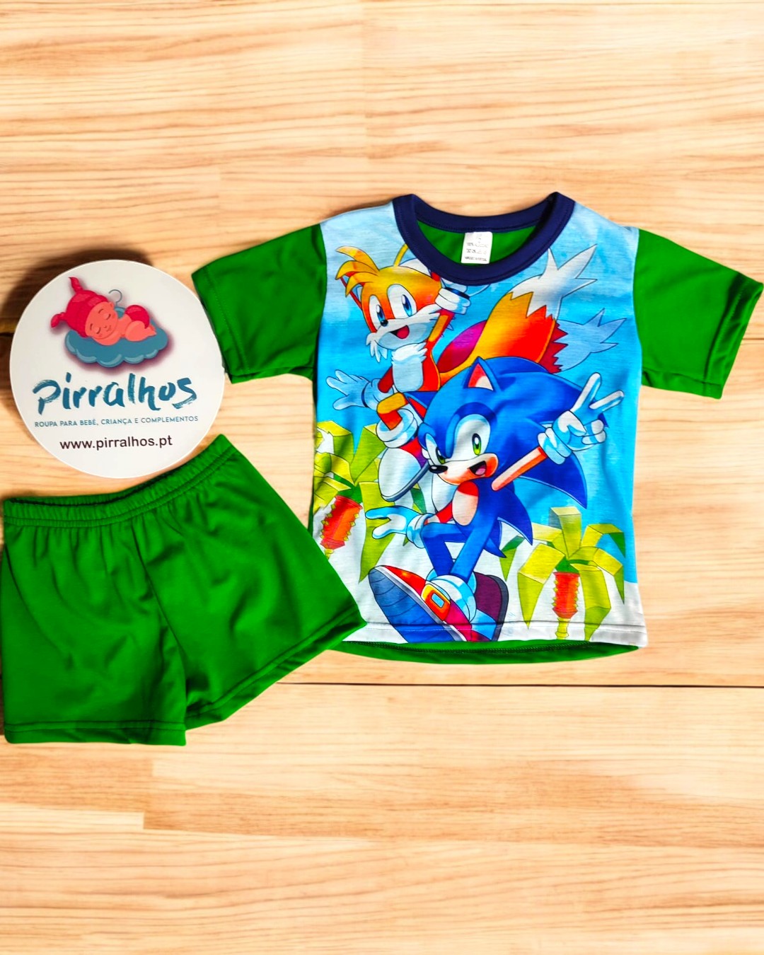 Conjunto infantil com t-shirt do Sonic e calções verdes sobre fundo de madeira