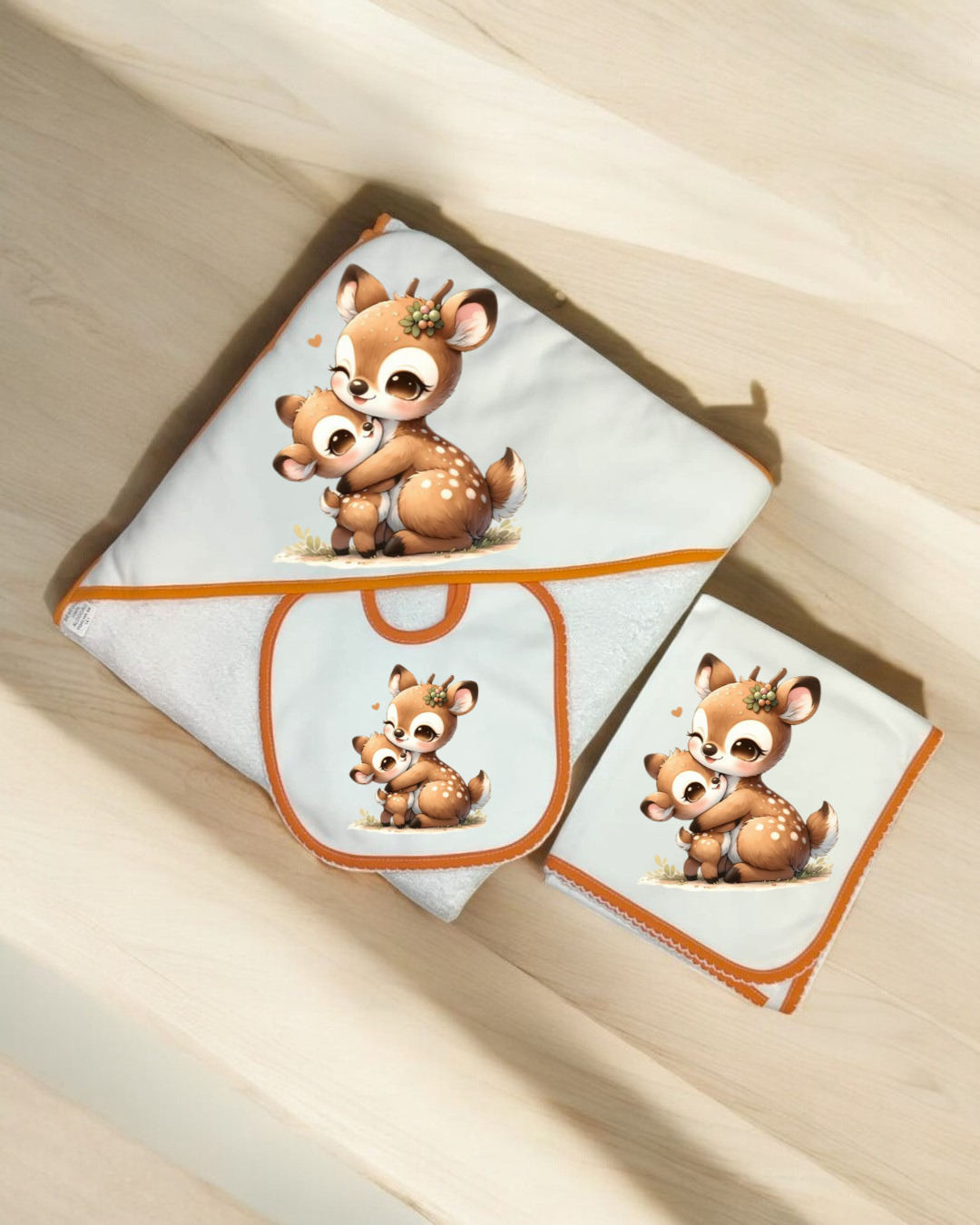 Conjunto de produtos para bebé com estampa de veados e bordas laranja.