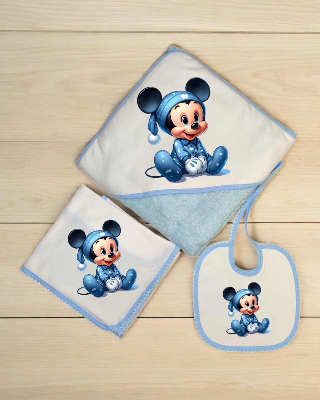 Toalha de bebé, fralda e bibe com estampado do Mickey Mouse em pijama azul.