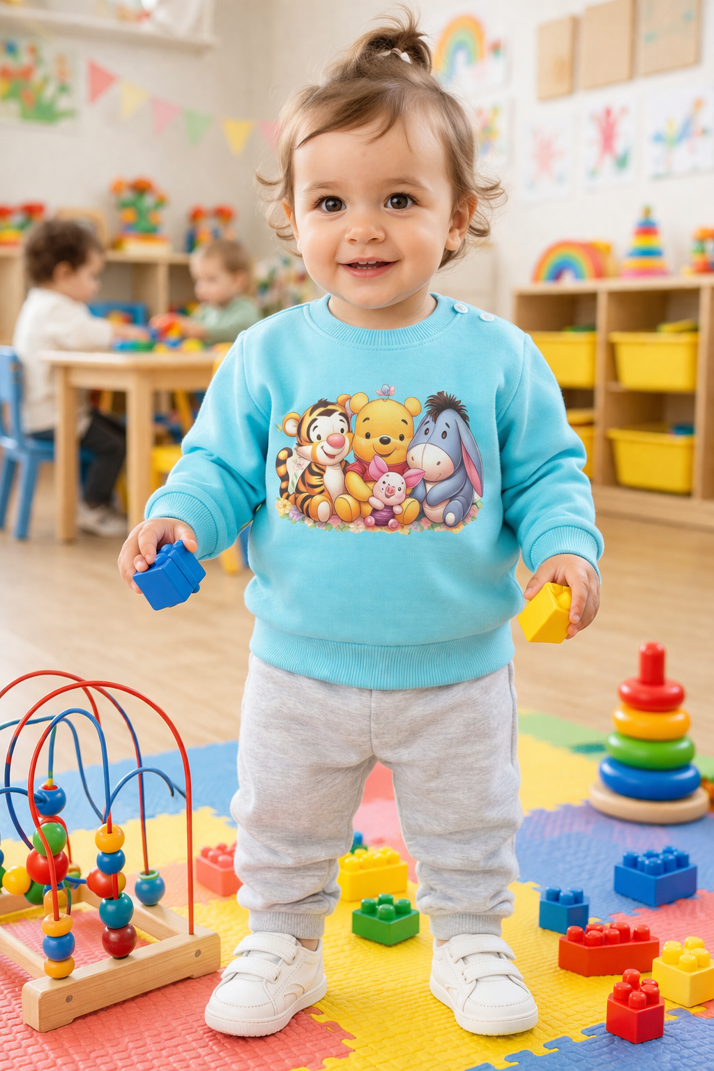 Criança com sweatshirt azul claro e calças cinza claro numa sala de brincadeiras com blocos coloridos