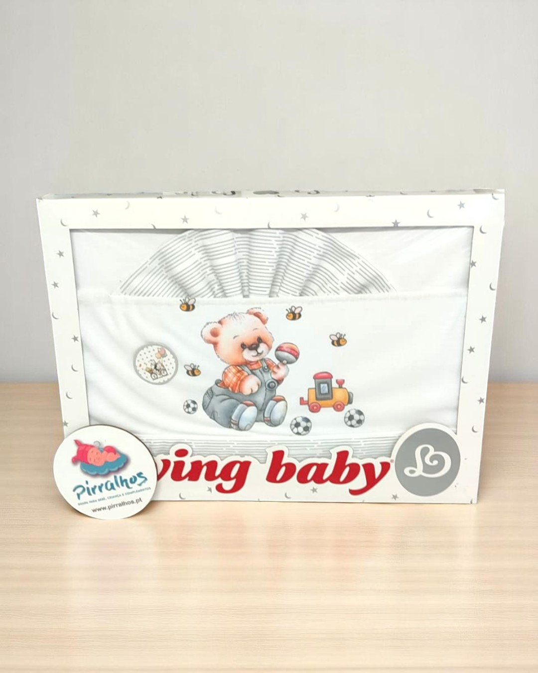 Conjunto de roupa de bebé com ursinho, bola e comboio, embalada em caixa branca com estrelas cinzentas