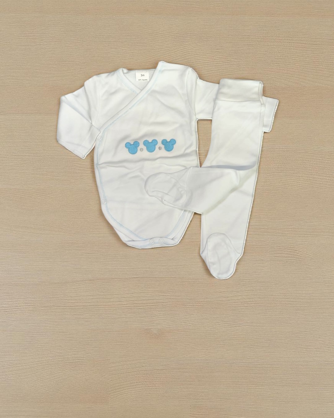 Conjunto de bebé branco com estampado azul e calças com pés.