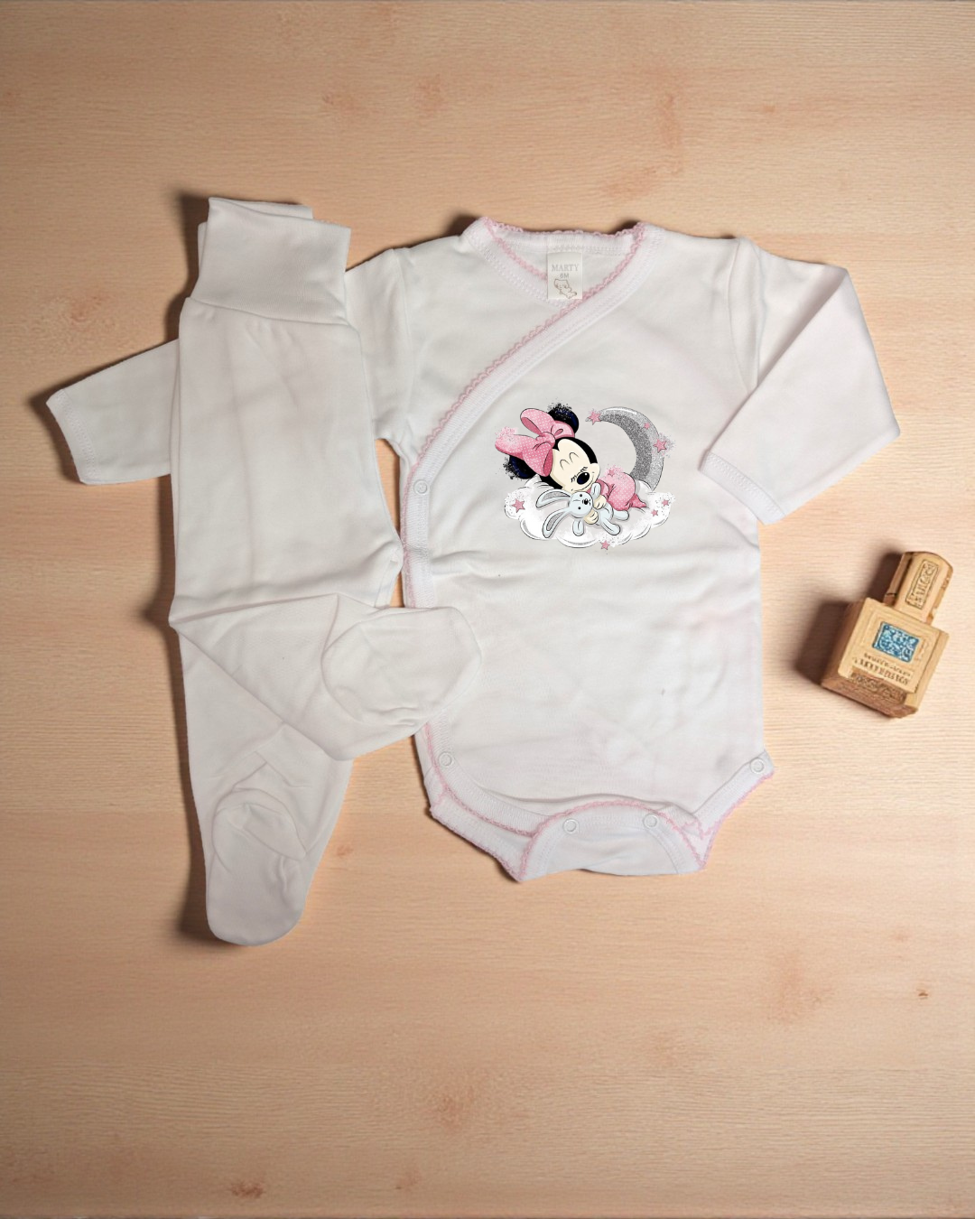 Conjunto de bebé com body branco de manga comprida com estampado da Minnie e calças brancas com pezinhos.