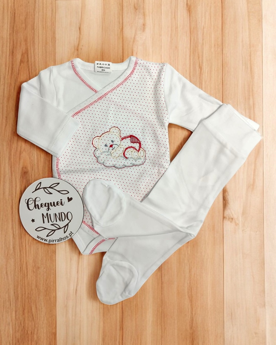 Conjunto roupa bebé body branco com urso e meias-calças brancas numa superfície de madeira
