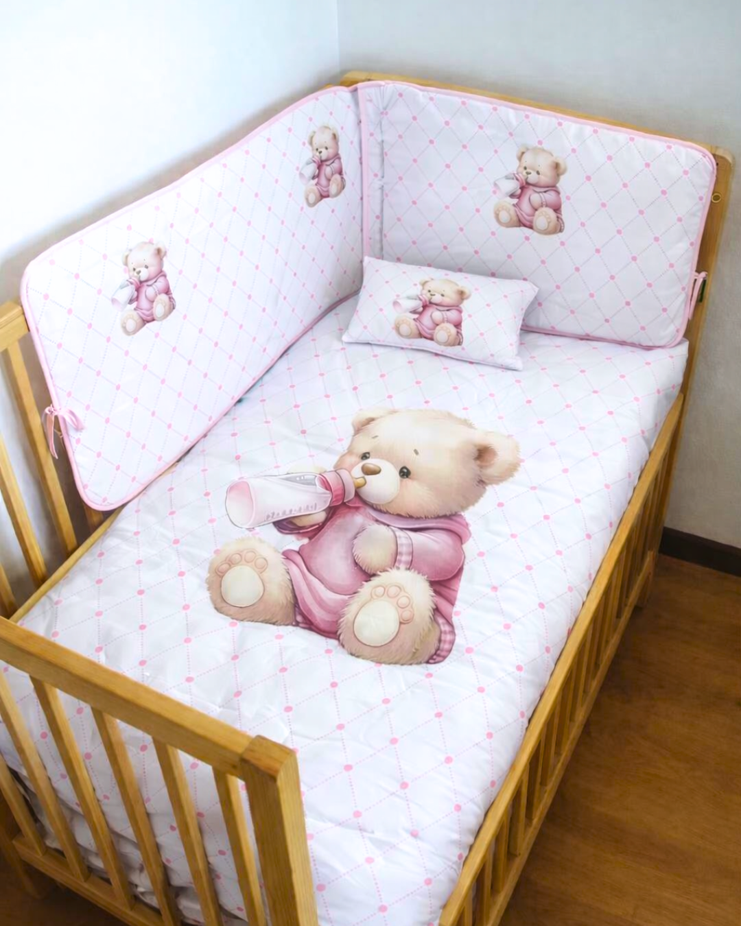 Berço de madeira com roupa de cama infantil com ursinhos e padrão xadrez rosa