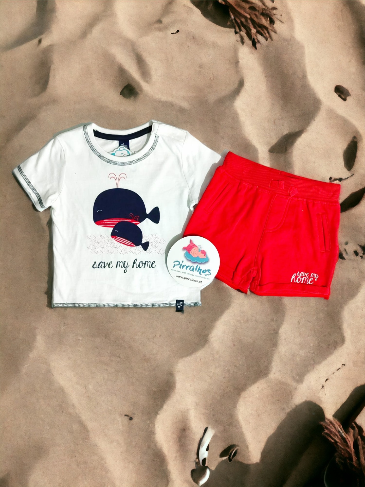 Conjunto infantil t-shirt branca estampada e calções vermelhos sobre areia com conchas