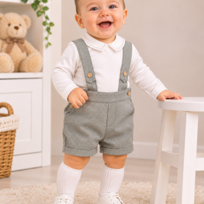 Bebé sorridente com roupa branca e cinzenta em ambiente interior acolhedor
