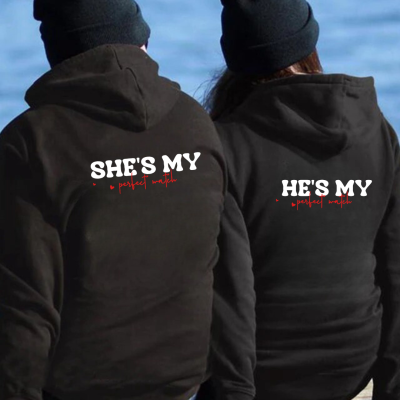 Casal com hoodies pretos e gorros pretos sentados de costas junto à água