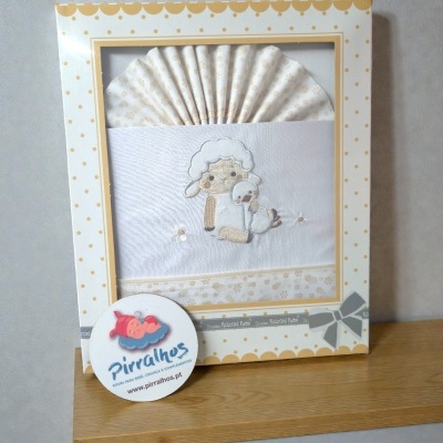 Conjunto de roupa de bebé branco e bege com bordado de ovelha e pato numa caixa com padrão de bolinhas.