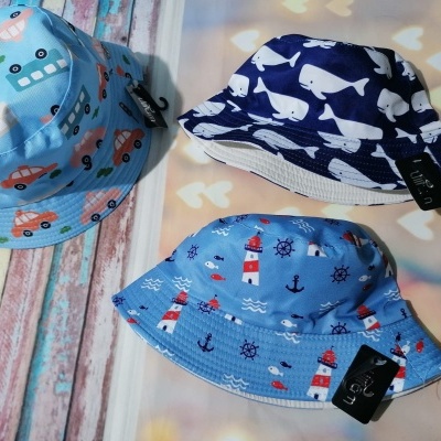 Três chapéus infantis estampados em tecido azul claro e azul escuro sobre fundo colorido