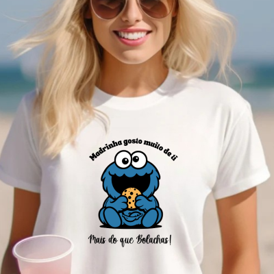 Camisola branca com estampa do Monstro das Bolachas e textos em português, usada por mulher loira com óculos de sol.