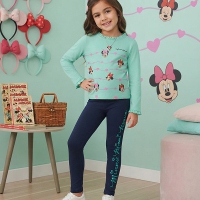 Menina com camisola verde-água e calças azul-marinho com estampa da Minnie Mouse, em quarto com decoração da Minnie.