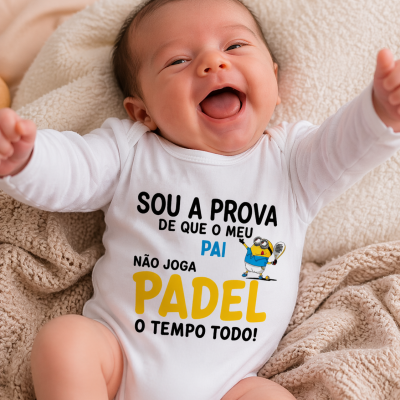 Bebé sorridente deitado com body branco com texto e ilustração de Minion a jogar padel