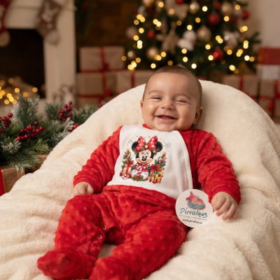 Bebé com fato natalício vermelho e branco com estampa Minnie Mouse sentado em almofada creme