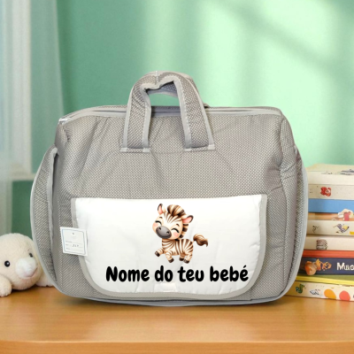 Mala de bebé cinzenta com bolso branco e desenho de zebra na mesa de madeira