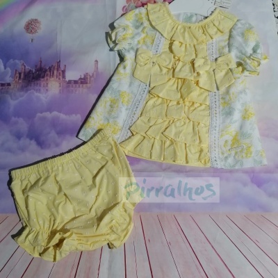 Conjunto de bebé amarelo com vestido folhado e calções, cenário de castelo e nuvens púrpuras