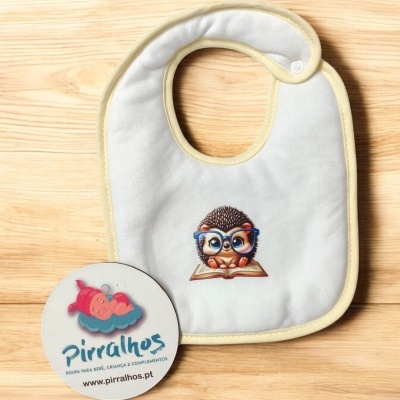 Babete branco com ouriço e etiqueta da Pirralhos sobre fundo de madeira