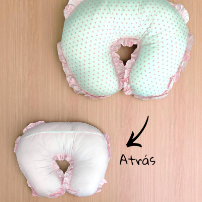 Almofada de amamentação em forma de U com padrão de estrelas rosa, texto 'Atrás', fundo madeira clara