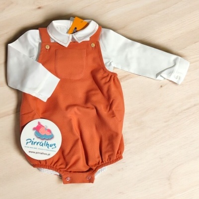 Conjunto de bebé branco e laranja sobre madeira clara