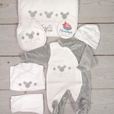 Conjunto de roupa de bebé branco e cinzento com estampas de ratinhos e texto A minha primeira roupinha, sobre piso de madeira.