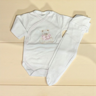 Conjunto de roupa de bebé branca com body e calças sobre superfície de madeira