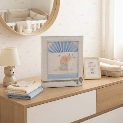 Cômoda com candeeiro em forma de urso, roupa azul e creme dobrada, caixa decorada com desenho de cão e moldura com ilustração de balão aerostático.