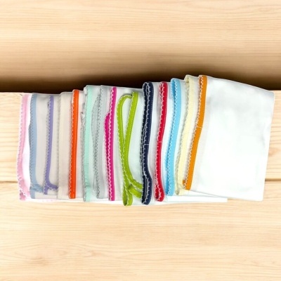 Lenços brancos com bordas coloridas variados sobre madeira