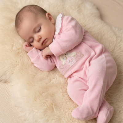 Bebé a dormir com pijama rosa em tecido macio sobre tapete felpudo creme