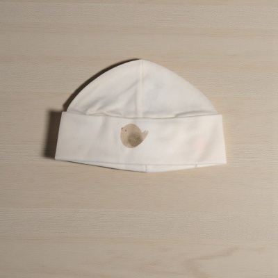 Gorro branco para bebé com desenho de pássaro sobre madeira clara