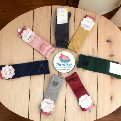 Sete pares de meias coloridas em círculo sobre mesa redonda de madeira clara