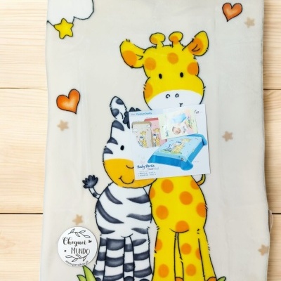 Cobertor com estampa de girafa e zebra coloridos sobre madeira clara.