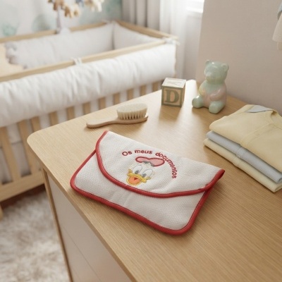 Necessaire branca com bordas vermelhas e imagem do Pato Donald com texto Os meus documentos sobre cómoda de madeira clara