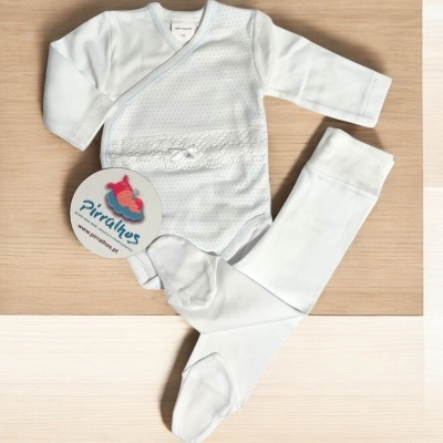 Conjunto de roupa para bebé branca com etiqueta Pirilitos sobre madeira.