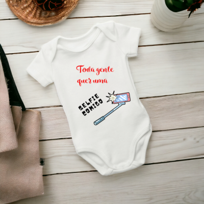 Body branco para bebé com texto e desenho colorido sobre superfície de madeira clara