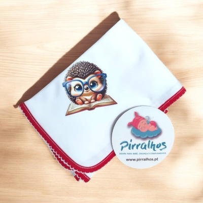 Manta branca com estampa de ouriço e etiqueta redonda sobre superfície de madeira.