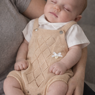 Bebé adormecido com fato de malha bege e camisa branca