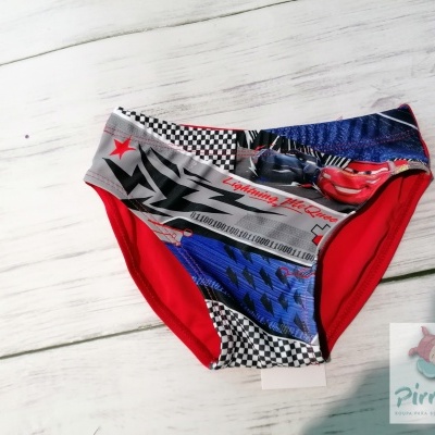 Cuecas de criança com estampas do filme Cars, em tecido colorido, sobre fundo de madeira clara