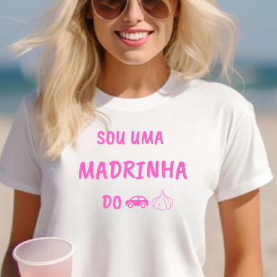 Mulher loira com óculos de sol e t-shirt branca com texto em rosa na praia.