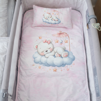 Berço com roupa de cama rosa e estampa de ursos em nuvens