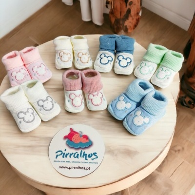 Meias de bebé coloridas com padrão de rato sobre mesa de madeira redonda