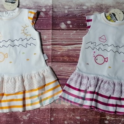 Dois vestidos infantis brancos com estampas e saias riscas amarelo e rosa sobre fundo de madeira