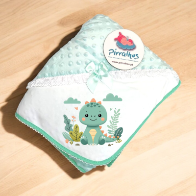 Manta infantil verde com desenho de dinossauro e etiqueta da marca Pirralhos