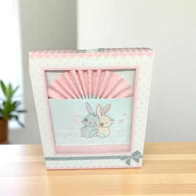 Jogo de roupa de cama para bebé com padrão rosa e ilustração de dois coelhos embrulhado numa caixa branca e rosa