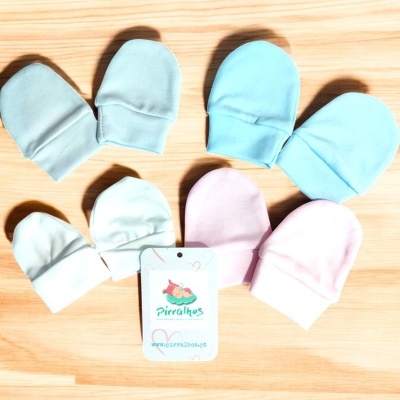 Set de sete luvas de criança em várias cores com etiqueta da marca Pirralhos sobre madeira clara