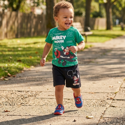 Menino a correr com roupa e sapatilhas infantis temáticas de Mickey Mouse e Homem-Aranha