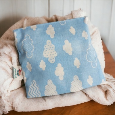 Bolsa de tecido azul com padrão de nuvens brancas sobre toalha bege numa superfície de madeira